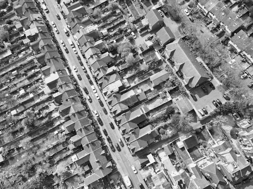 A narrow terraced street in a London neighborhood viewed from above, featuring a row of small residential houses with pitched roofs, some of which have skylights and chimneys. The houses have varied f